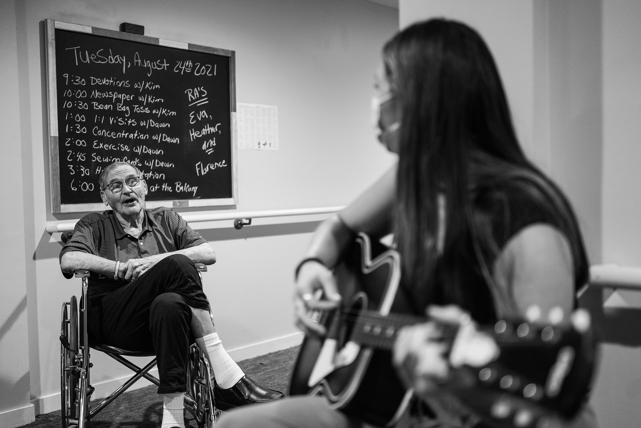 senior man in wheelchair singing along to guitar music played by a music therapist