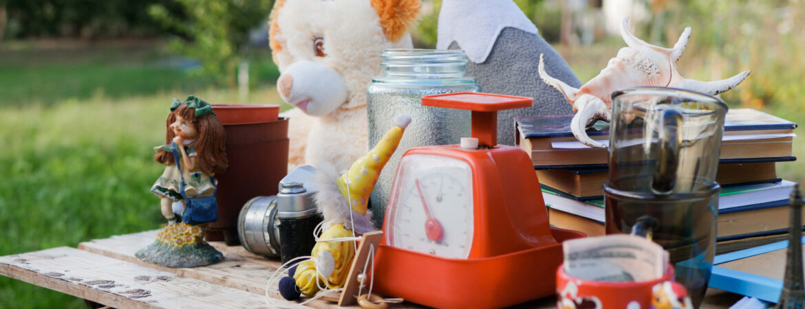 A variety of items including toys, a clock, and books on a table in a garden.